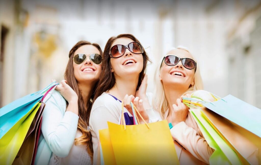 Three stylish women with sunglasses and shopping bags, highlighting a Mother's Day event at Marina Inn.