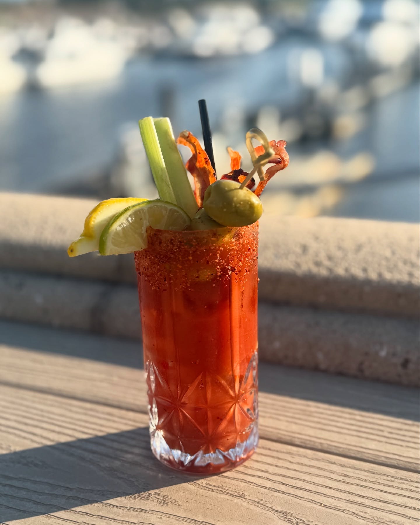 a Bloody Mary cocktail with garnishes on a wooden table