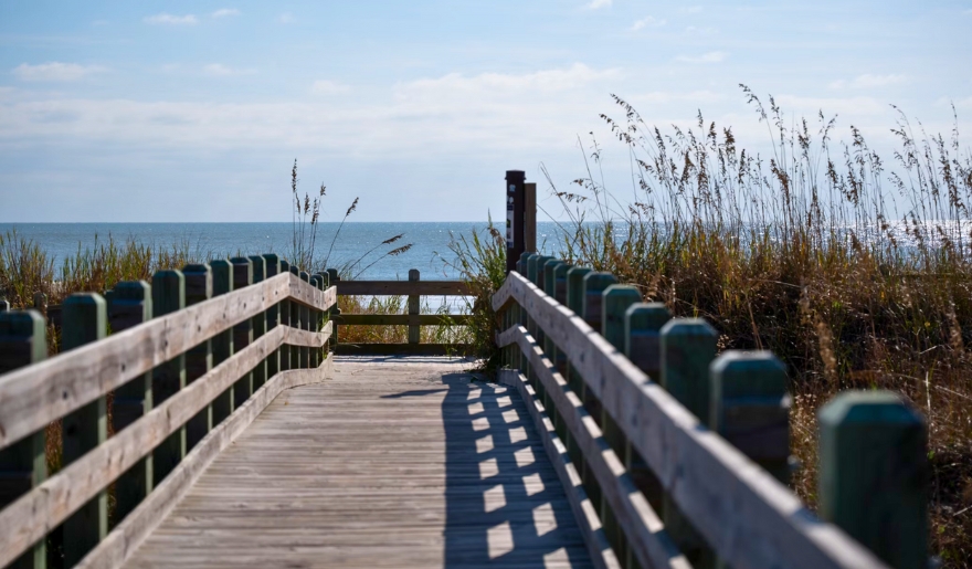A wooden boardwalk stretches toward the ocean at Myrtle Beach State Park, ideal for family outings and exploration.