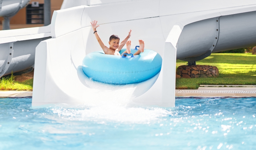 A child joyfully rides a water slide at Myrtle Waves Water Park, splashing into the pool below.