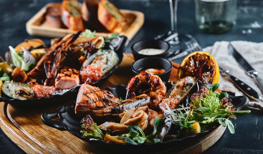 Delicious grilled seafood in a black pan, paired with bread and wine, showcasing nearby dining options for a romantic getaway.
