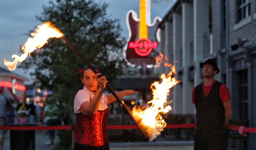 A woman handed a stick with flame performing in Broadway at the Beach during summer, embracing the best time to visit Myrtle Beach