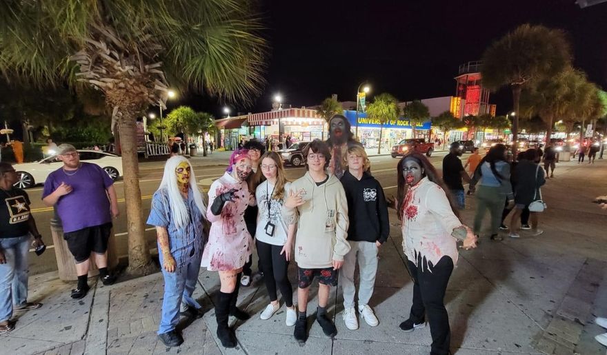 People in elaborate zombie costumes gather at Myrtle Beach, celebrating the Halloween spirit.