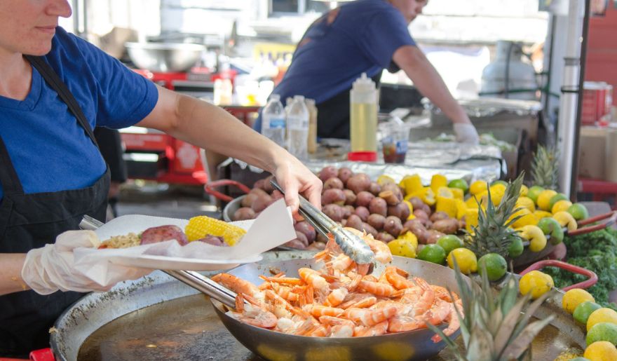 At Little River ShrimpFest food stand in Myrtle Beach, a woman in an apron skillfully prepares delicious food amidst the October atmosphere.