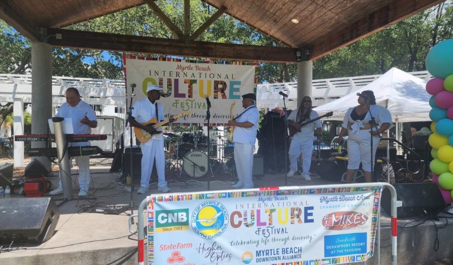 A lively band plays on stage at a festival in Myrtle Beach, October, captivating the audience with their vibrant performance.