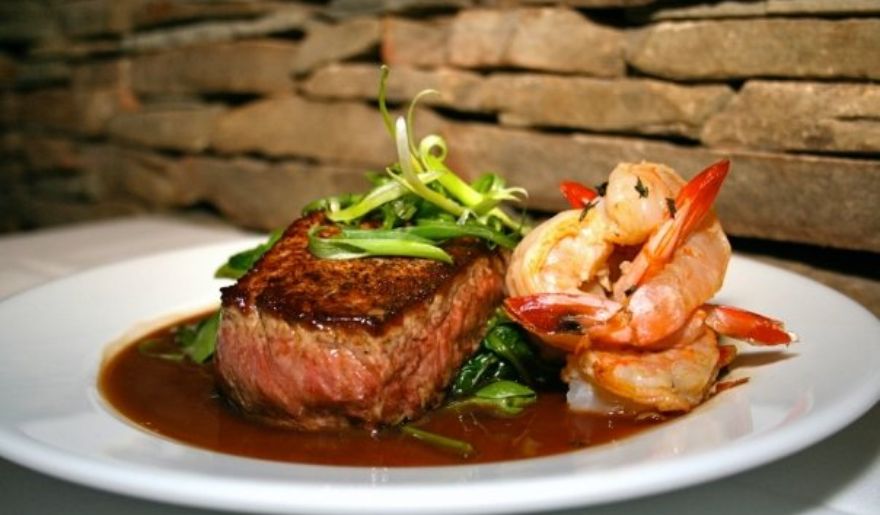 A gourmet dish showcasing a juicy steak paired with tender shrimp, served by Aspen Grille.