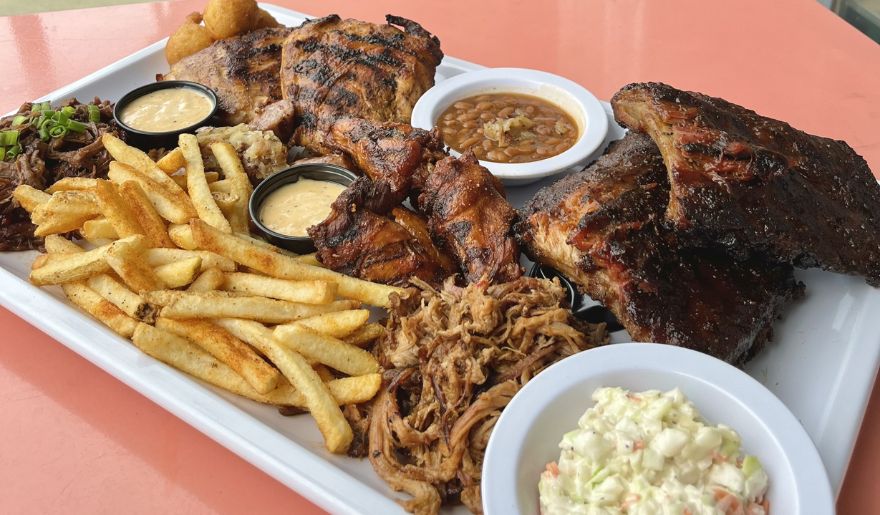 A delicious platter featuring tender ribs, crispy fries, and fresh coleslaw, cooked by Bubba’s Fish Camp & Smokehouse.