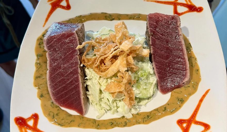 A serving of tuna paired with coleslaw on a plate, showcasing a delicious meal available in Chive Blossom