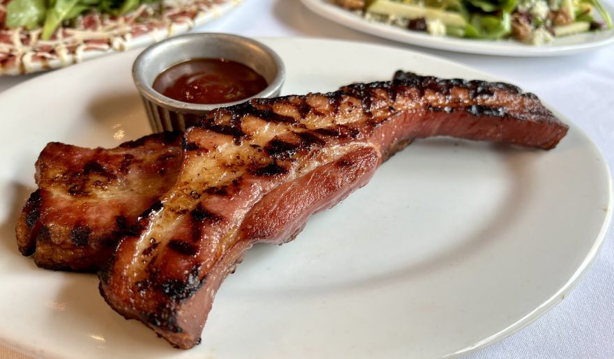 A delicious serving of meat on a plate, paired with a vibrant salad, representing one of the best places to eat in Myrtle Beach 