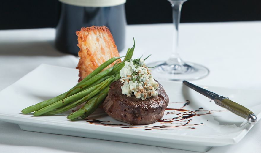 A delicious steak accompanied by green beans and a glass of wine, served by Seablue one of the best places to eat in Myrtle Beach.