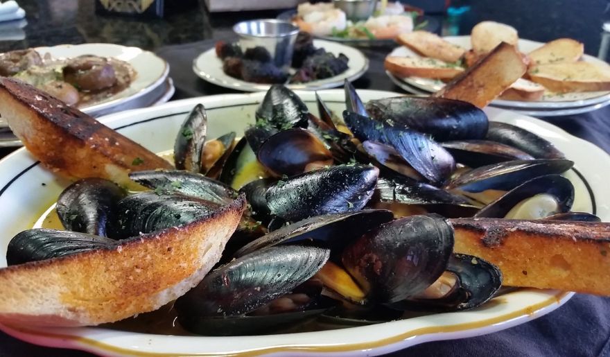 A plate of mussels accompanied by bread, served by The Library Restaurant, showcasing a dining experience in Myrtle Beach.