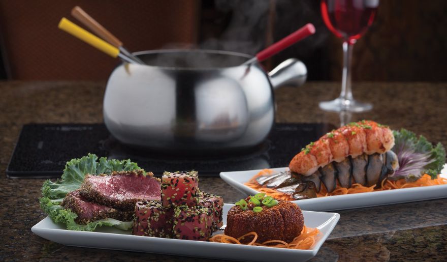 Two plates of delicious food beside a pot of boiling water, highlighting The Melting Pot Myrtle Beach culinary scene.