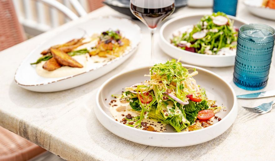 A beautifully arranged table featuring delicious food alongside a glass of wine served by Wicked Tuna, highlighting one of the best places to eat in Myrtle Beach.