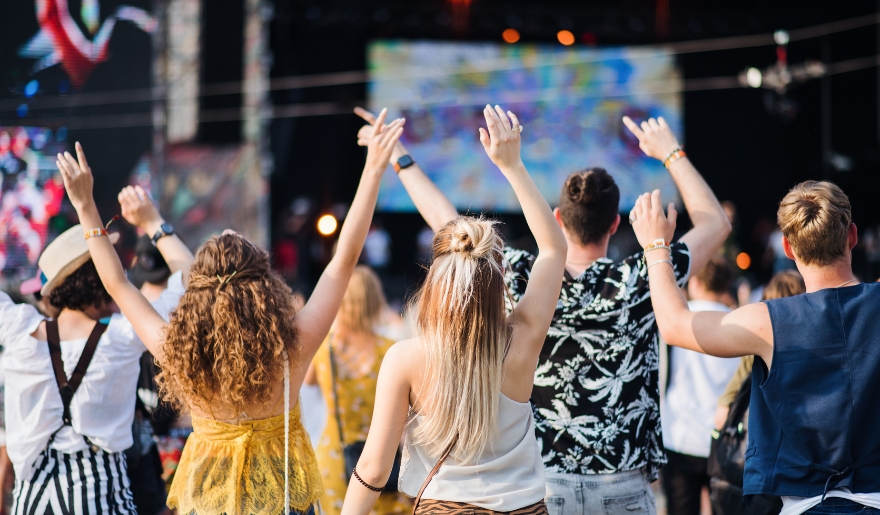 A crowd of people at a summer music festival in Myrtle Beach, with hands raised, enjoying the vibrant atmosphere.