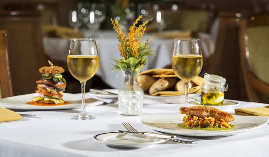 A beautifully set table featuring two plates of gourmet food and two elegant glasses of wine, perfect for Myrtle Beach bachelor party experience.