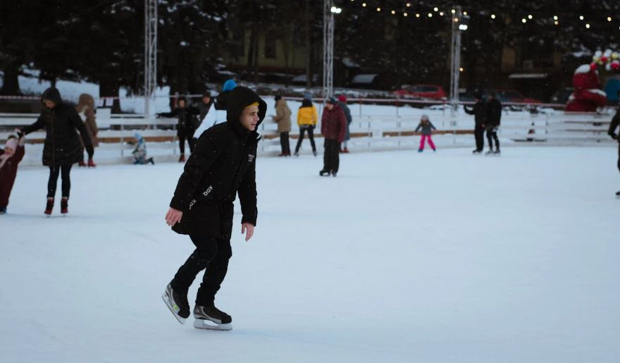 A person gracefully skating on an illuminated ice rink at night, during the Myrtle Beach Christmas
