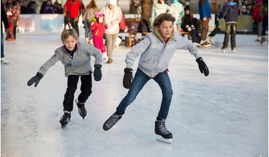 Two children skate joyfully on an ice rink, enjoying the Myrtle Beach Winter Wonderland.