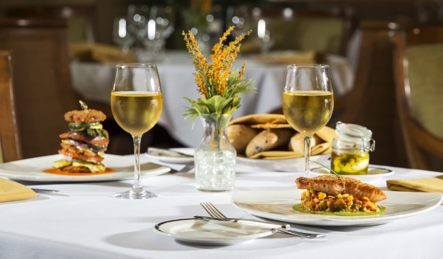 An inviting table featuring two plates of gourmet food and two glasses of wine, highlighting local dining in Myrtle Beach.