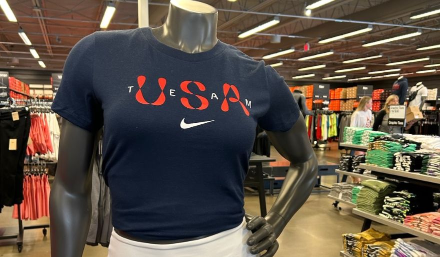 A store mannequin showcases a Nike t-shirt, inviting shoppers to explore holiday deals at Tanger Outlets.