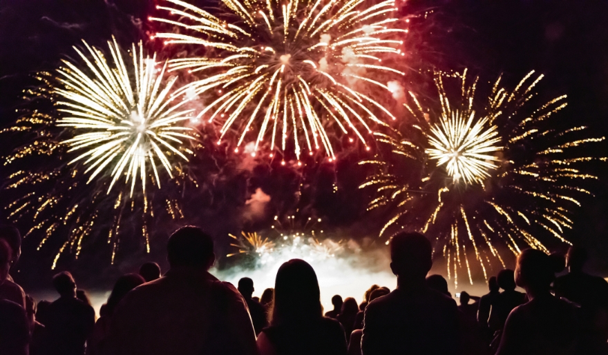 A large crowd gathers at Barefoot Landing, Myrtle Beach, watching colorful fireworks illuminate the night sky during winter festivities.