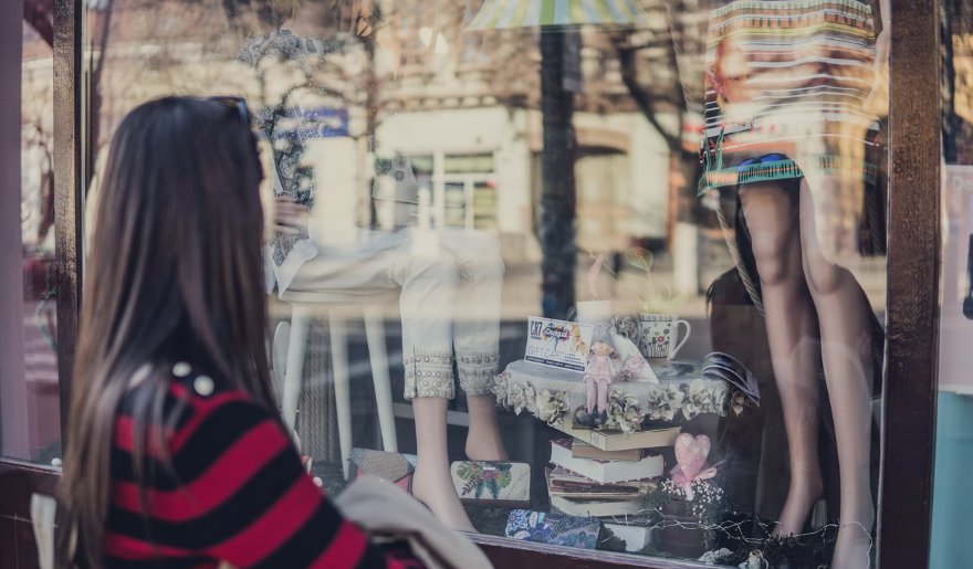 A woman gazes at a vibrant window display of clothing in the Island Road Shopping District, Myrtle Beach.