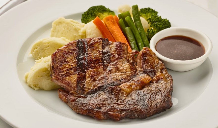 A plate featuring a juicy steak, creamy mashed potatoes, vibrant carrots, and fresh broccoli at Aspen Grille, Myrtle Beach.