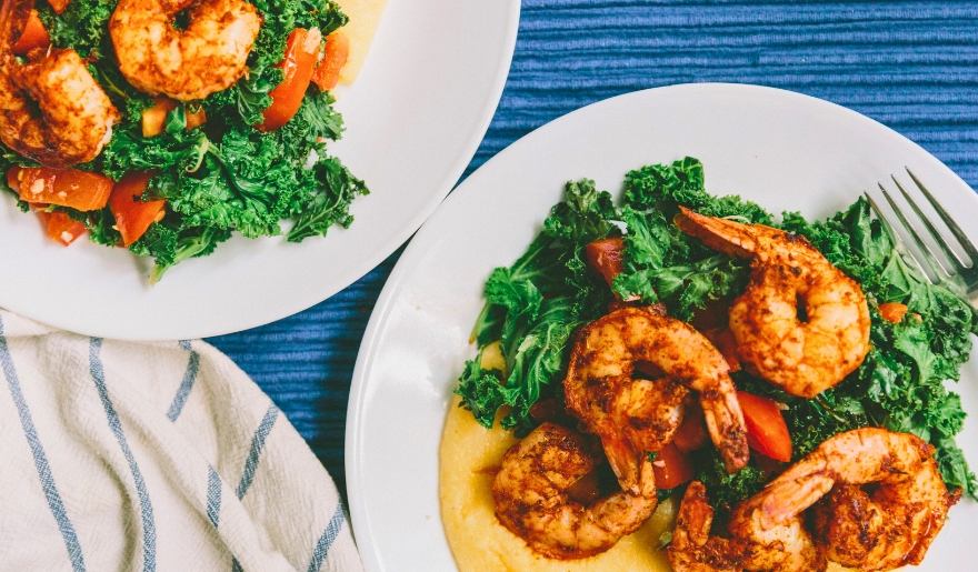 Two plates adorned with shrimp and fresh greens, highlighting a culinary offering from Hook & Barrel in Myrtle Beach.