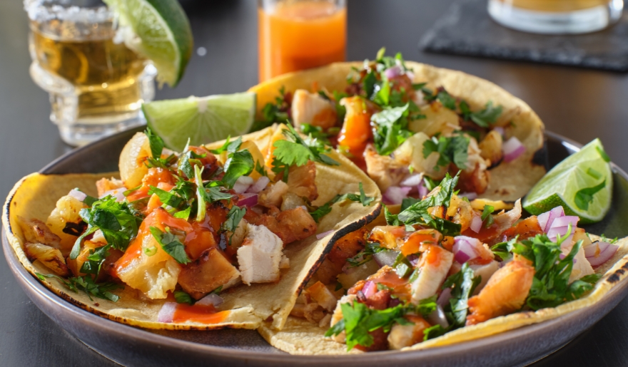 A plate featuring three tacos topped with fresh vegetables, seafoods and lime, showcasing a dish from Lulu’s North Myrtle Beach.