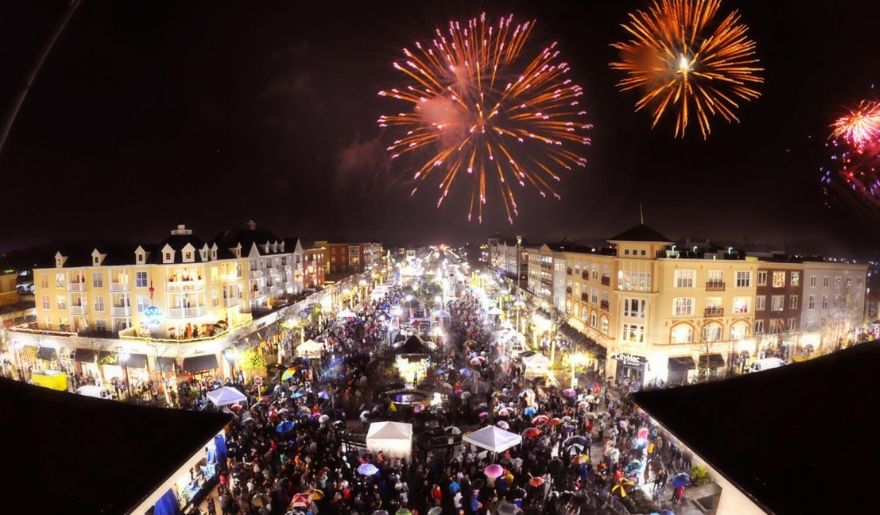 A vibrant display of fireworks lights up the night above a crowded street, celebrating New Year’s at Myrtle Beach's Market Common.