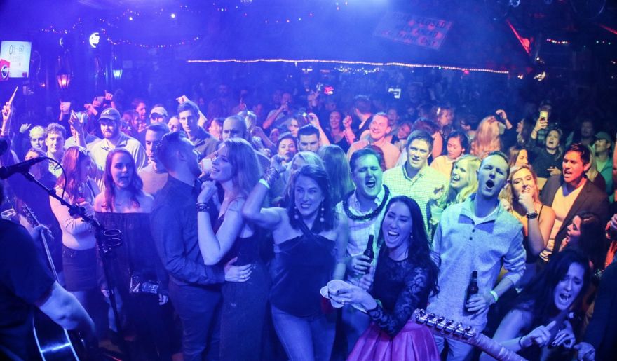 A lively crowd at Tin Roof Myrtle Beach celebrates New Year's Eve, singing and dancing joyfully in a vibrant nightclub atmosphere.