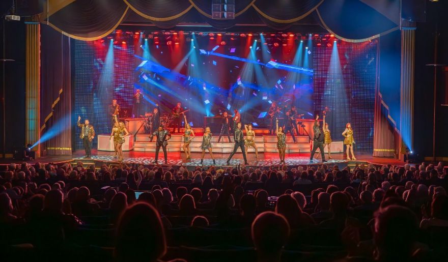 The cast of a musical performing energetically on stage, showcasing their talent and enthusiasm for the audience perfect for couple tours.