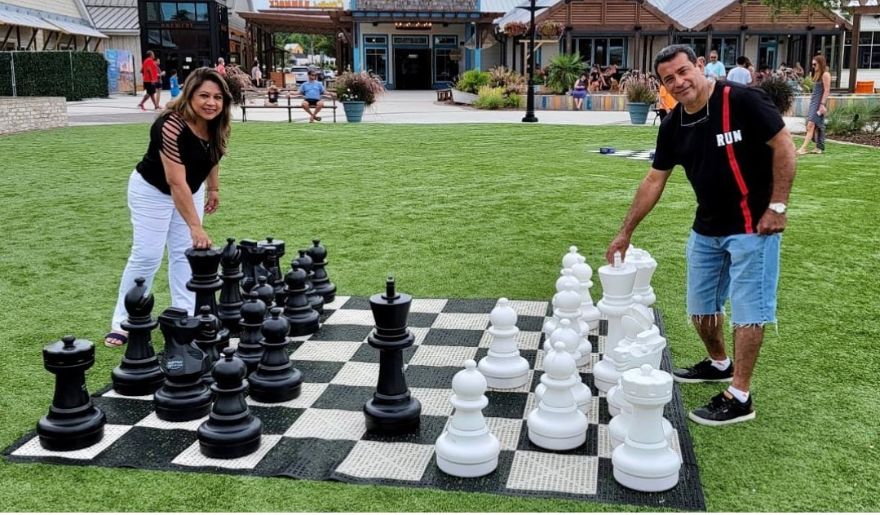 A couple plays chess on an oversized board at Barefoot Landing, showcasing a fun activity for couples in Myrtle Beach.