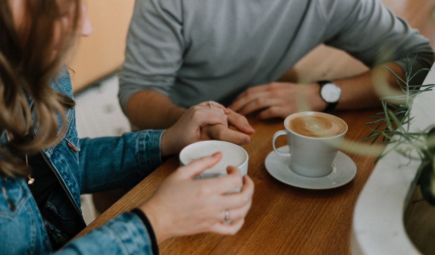 A couple enjoying coffee at a table in a cozy cafe, perfect for couples exploring Myrtle Beach's hidden gems.