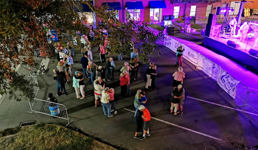 A lively couple gathers around a stage at night, enjoying the vibrant atmosphere of Georgetown's historic event.