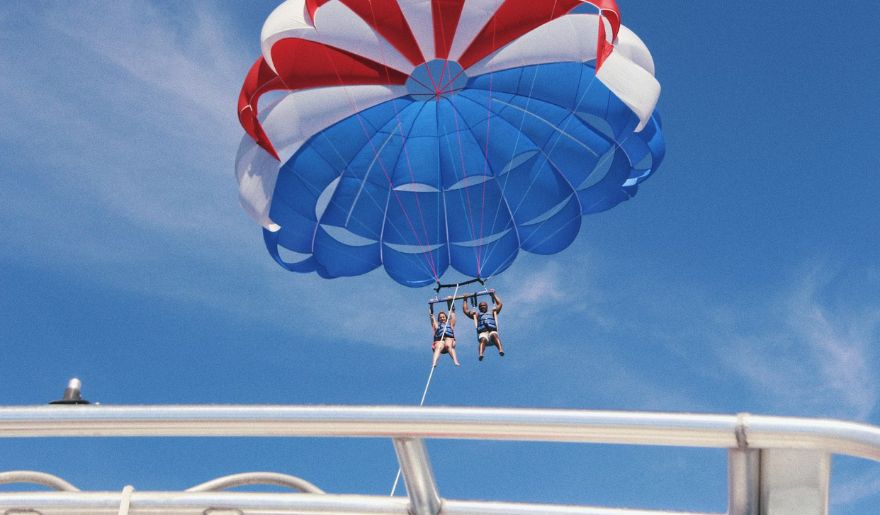 A lovely couple enjoys parasailing against a clear blue sky, showcasing adventure in Myrtle Beach.