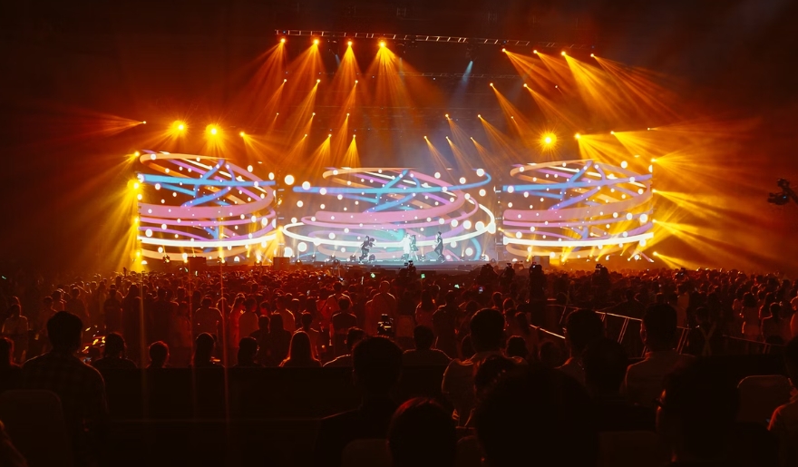 A vibrant crowd watches a concert at Alabama Theatre, with colorful lights creating a lively atmosphere in Myrtle Beach.