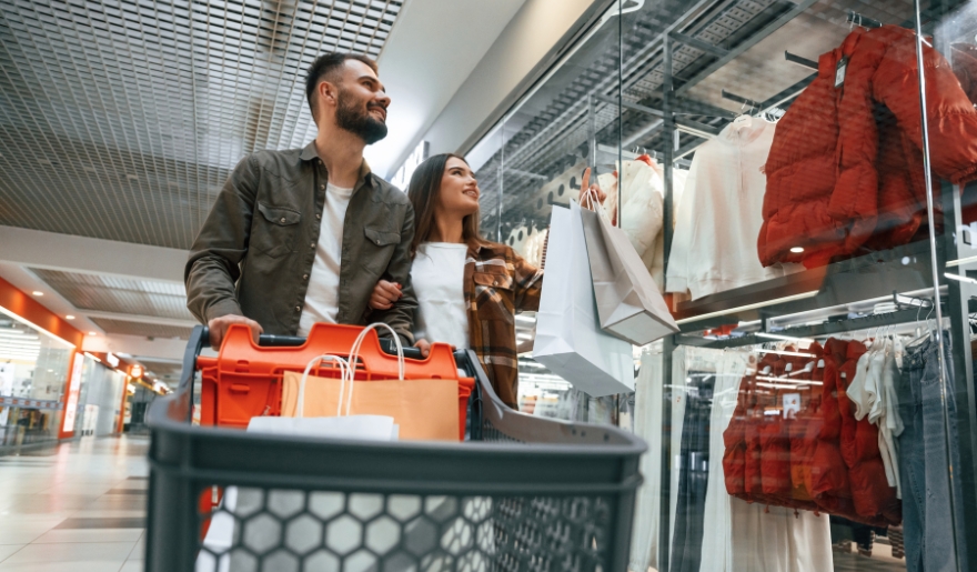 A couple walks through a mall with shopping bags, exploring the vibrant atmosphere of Barefoot Landing in Myrtle Beach.