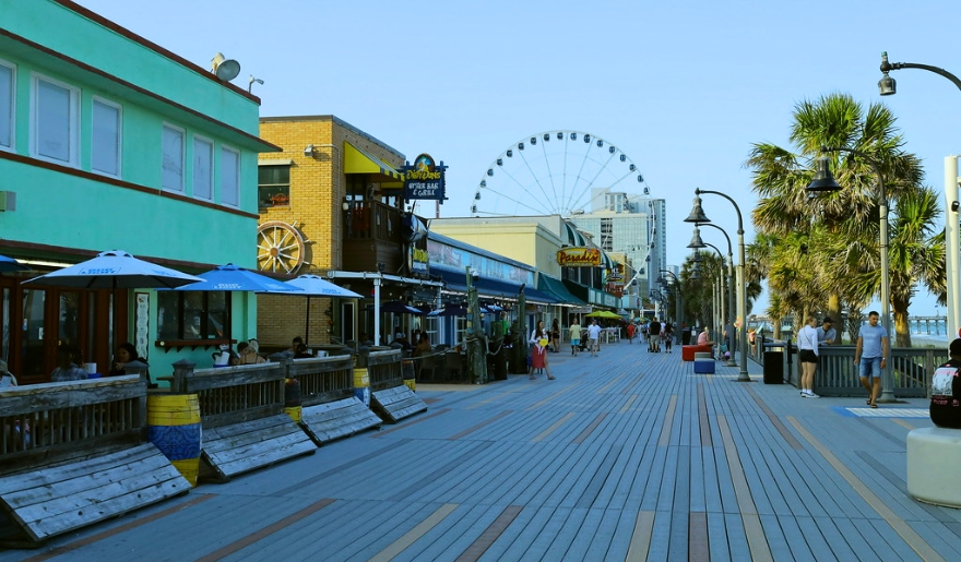 People walking along the Myrtle Beach boardwalk, surrounded by shops and ocean views, perfect for couples.