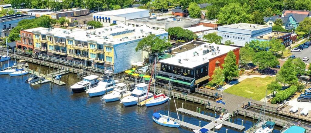 A scenic view of the marina in Charleston, SC, featuring boats docked against a backdrop of blue skies and historic buildings.