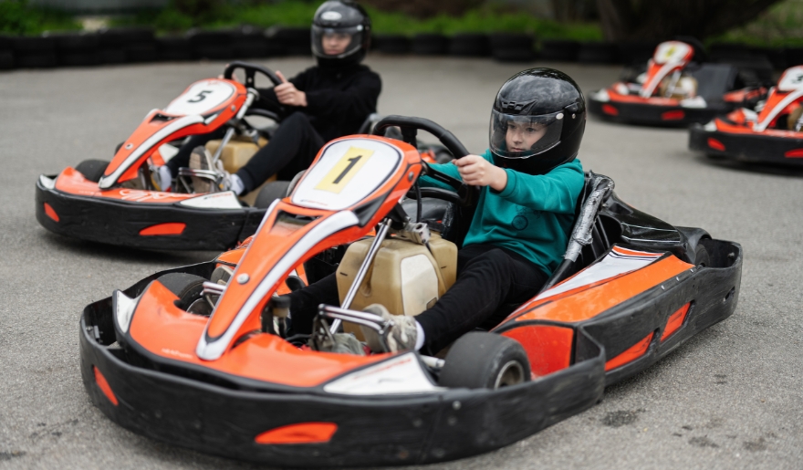 Two kids enjoying go kart racing on a track at Myrtle Beach Spring Break family-friendly attractions.