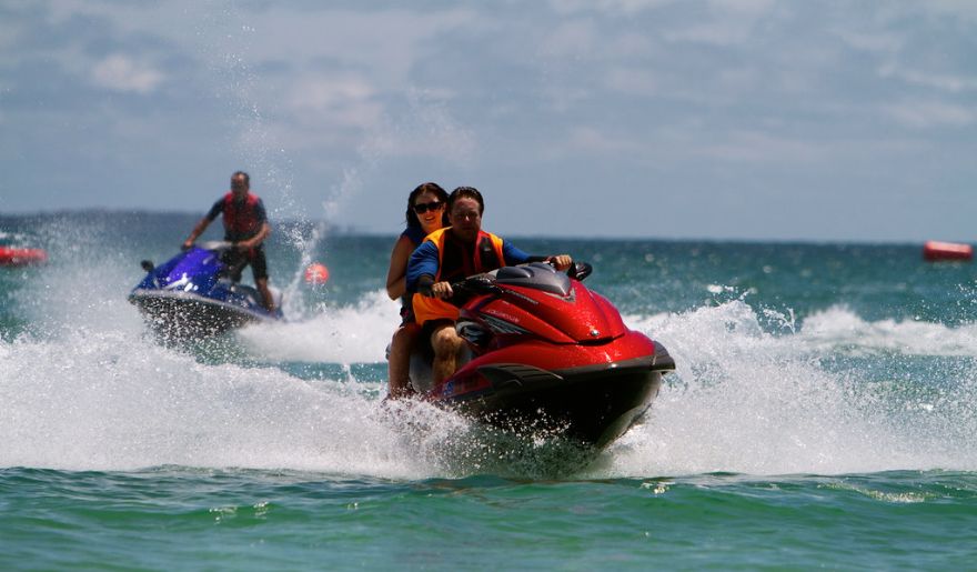 Two people enjoy riding jet skis across the ocean waves at Myrtle Beach, capturing the thrill of the moment.