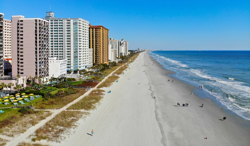 A scenic view of Myrtle Beach featuring tall buildings alongside a sandy beach, highlighting family activities at Grand Strand.
