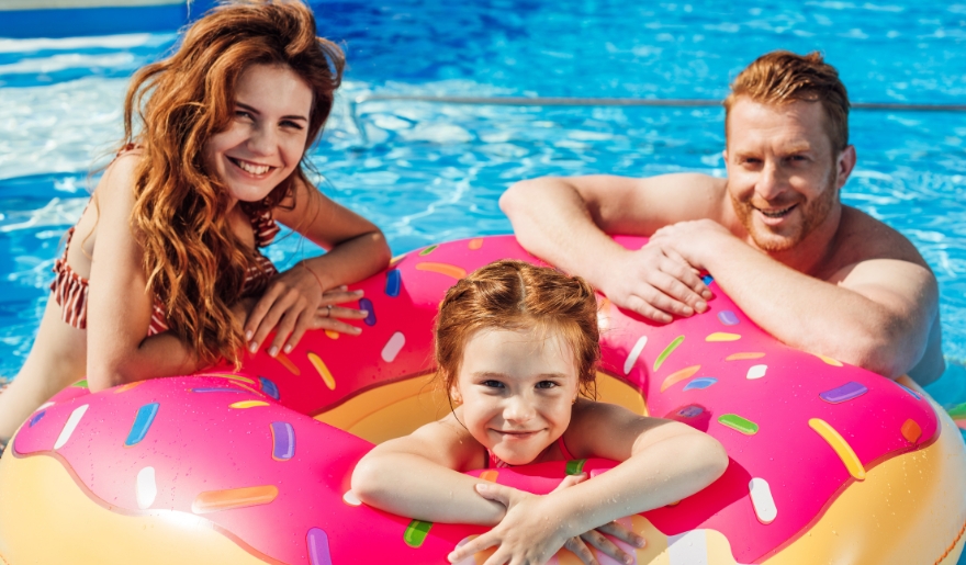 A joyful family splashes in a pool with a vibrant donut float, enjoying their time at Myrtle Waves Water Park, Myrtle Beach.