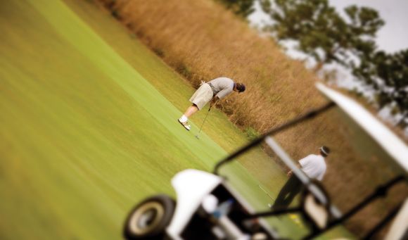 A golfer takes a shot on a vibrant green course, part of the Myrtle Beach Golf Trips experience.