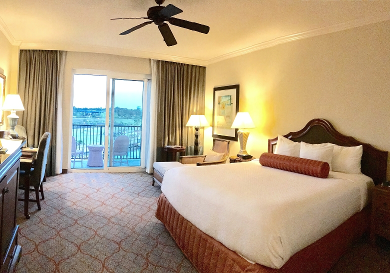 A cozy hotel room featuring a bed, television, and a private balcony overlooking Myrtle Beach.