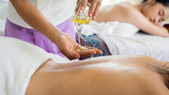 A woman enjoys a relaxing oil massage on her back in a serene spa setting at Marina Inn