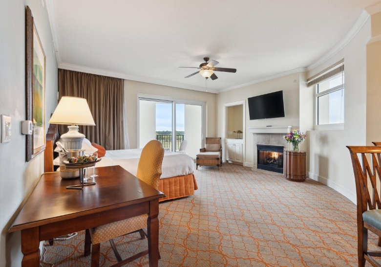 A stylish hotel room featuring a bed, desk, chair, and television, showcasing upscale furnishings in Marina Inn.