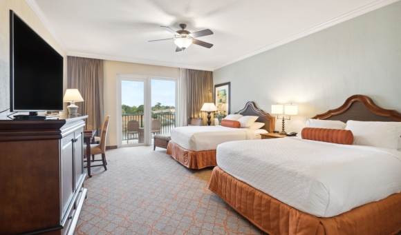 Two beds in a hotel room featuring a television and a balcony, ideal for a stay in Myrtle Beach condos for rent.