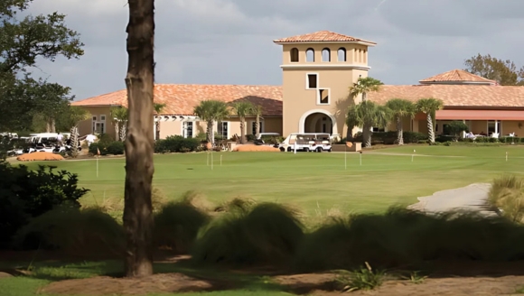 A scenic golf course featuring a large building in the background, highlighting the Grande Dunes Golf Club in Myrtle Beach.