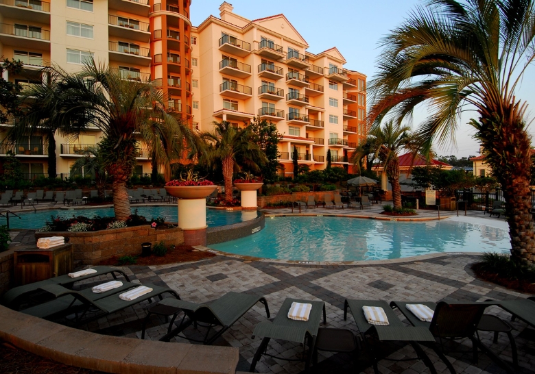 A tranquil resort pool with lounge chairs and palm trees, showcasing the luxury of Myrtle Beach's upscale condo rentals.